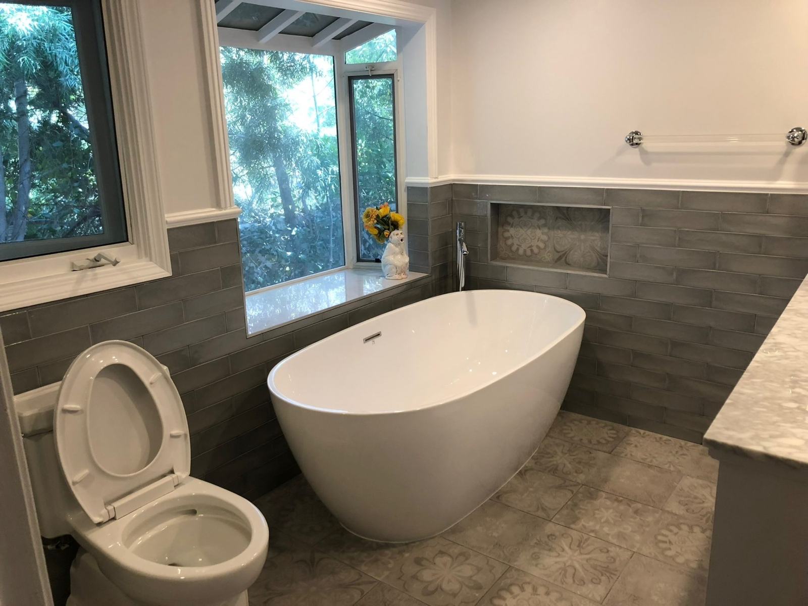Freestanding tub under a window in a remodeled bathroom