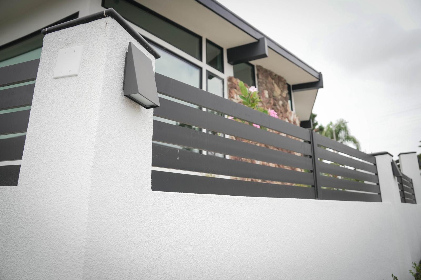 Stucco block wall pillar with light and horizontal slat fence