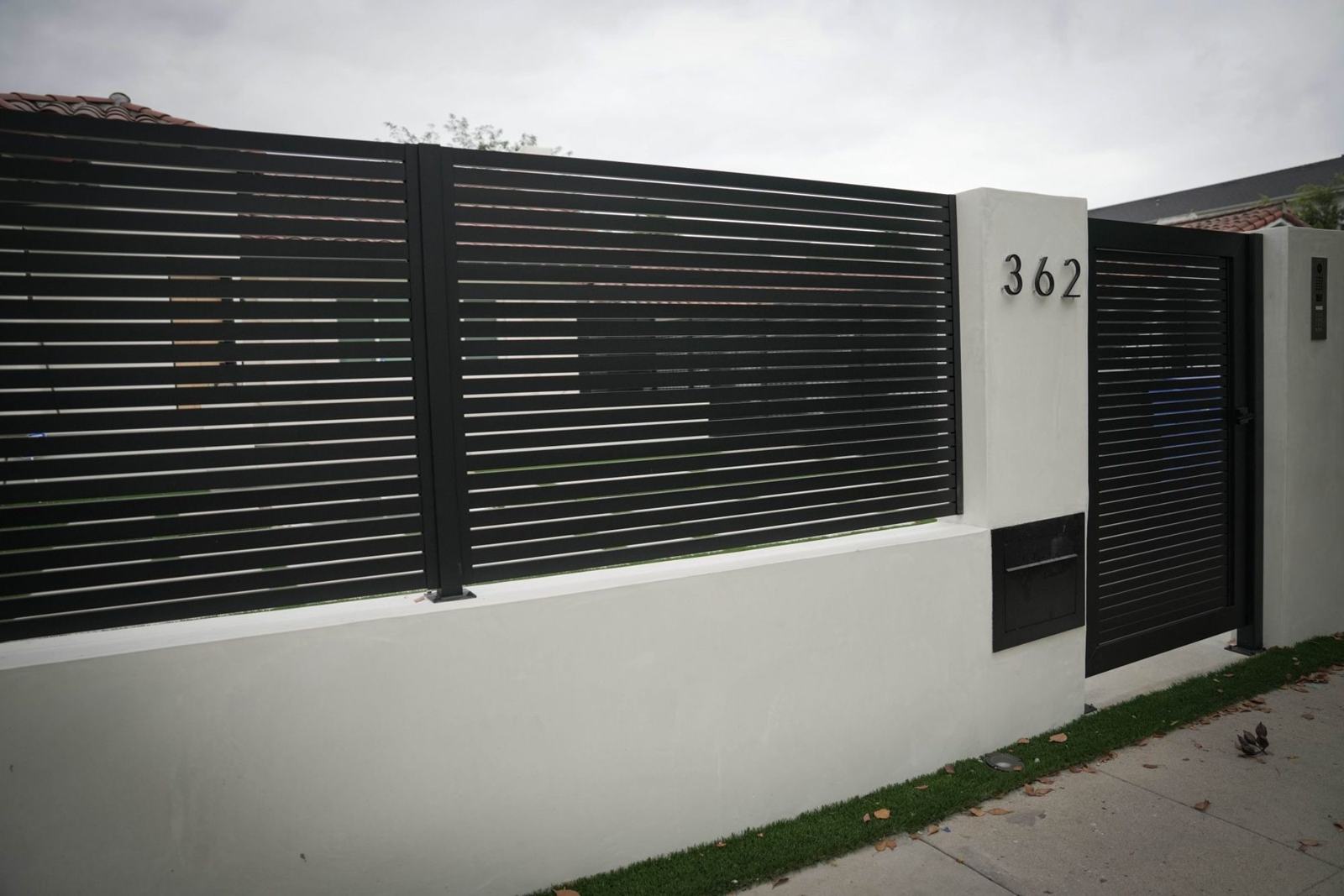 Stucco block wall with aluminum slat panels and built-in mailbox