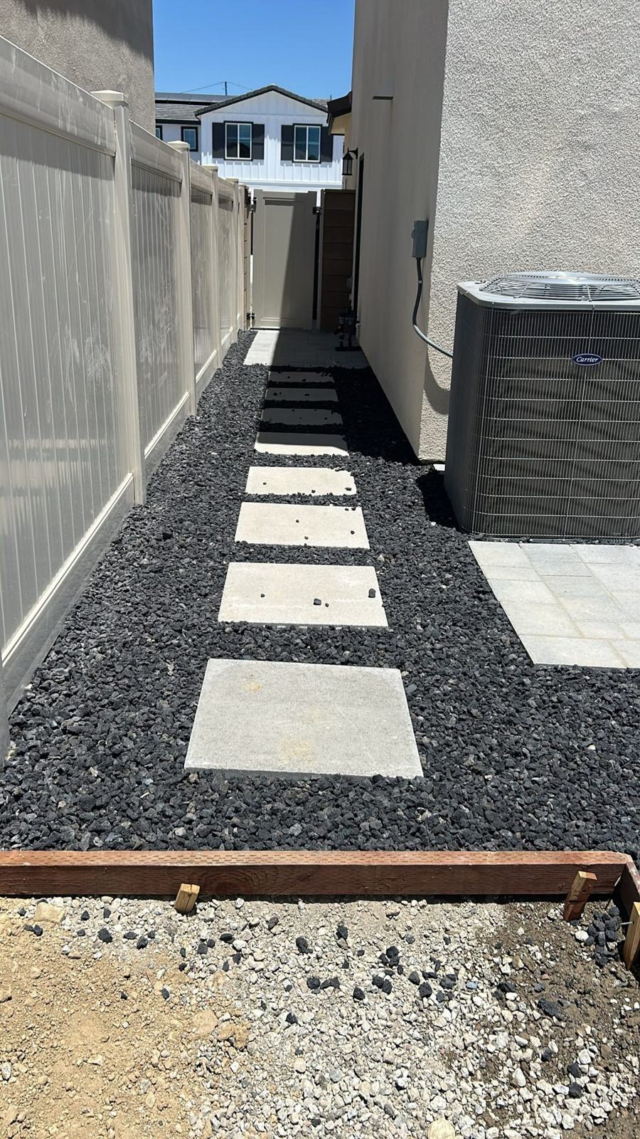 Concrete steppers set in black lava rock along a side yard